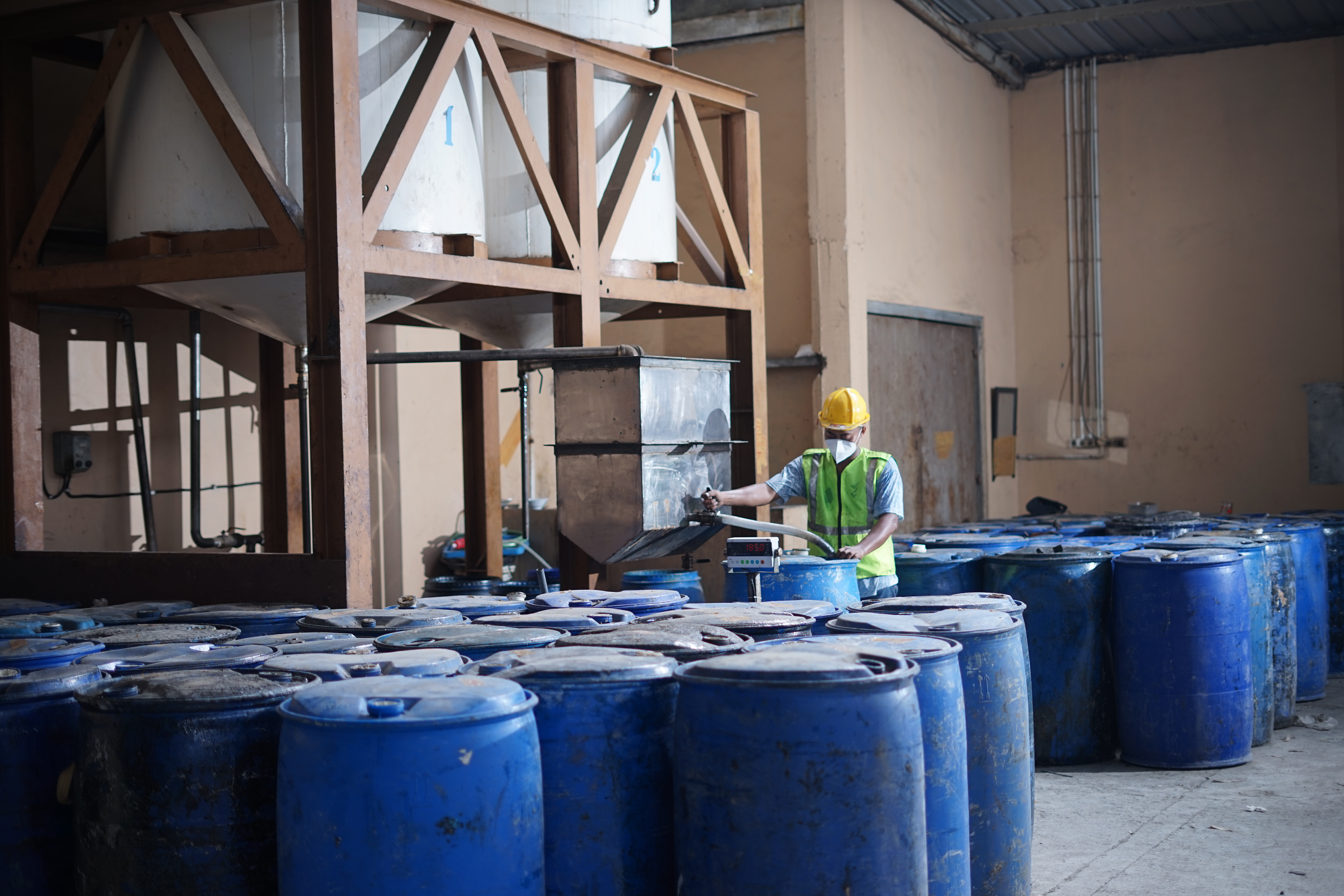 Worker filling gum rosin into blue barrel